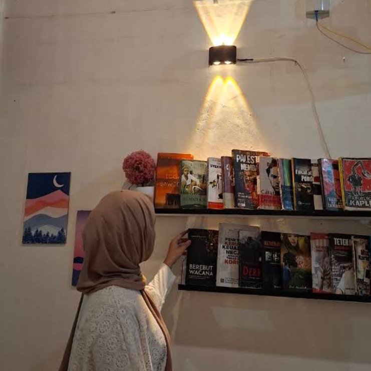 Pengunjung melihat koleksi buku di dalam kafe.