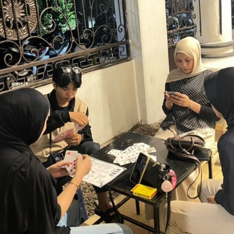 Teman-teman bermain kartu sambil berkumpul di kafe.