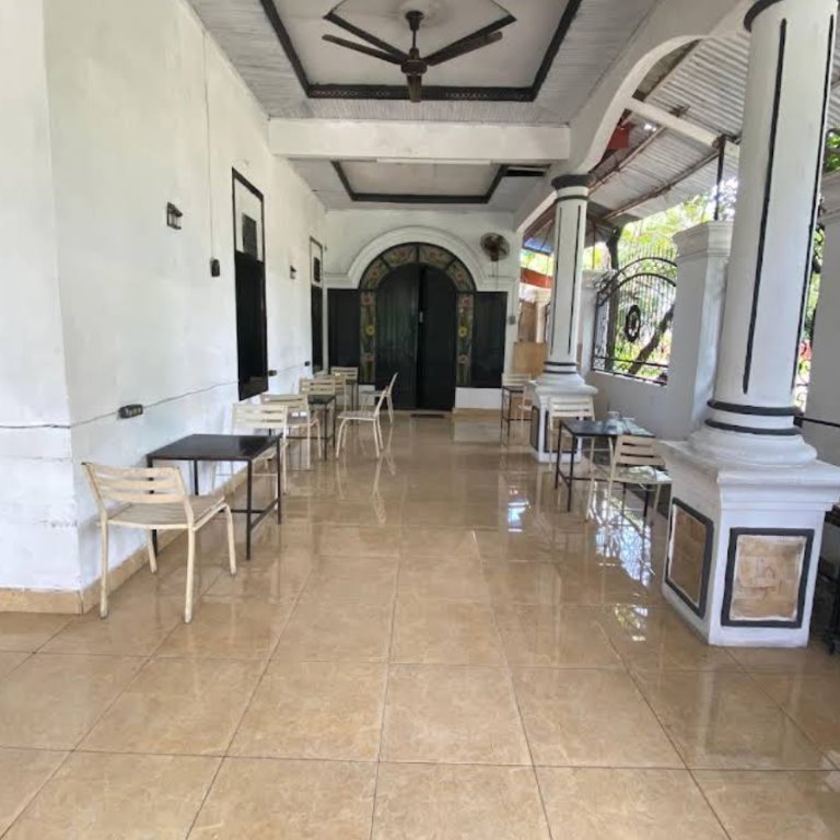 Area teras dengan meja, kursi, dan pilar putih.